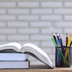 the pile of books, paper and pencil on the desk