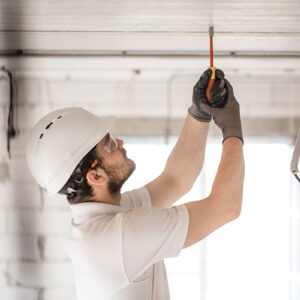 Electrician installer with a tool in his hands, working with cable on the construction site.