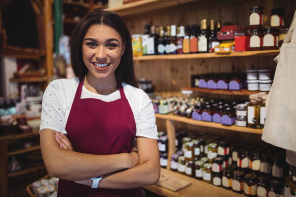 Portrait of female staff standing with arms crossed in super market