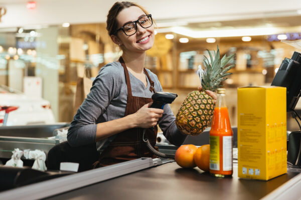 Happy female cashier scanning grocery items