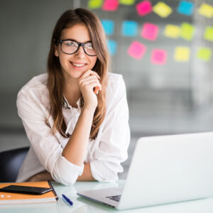 successful businesswoman working on laptop computer and thinks on new ideas in her office dressed up in white clothes